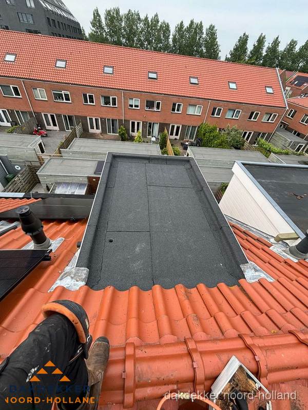 Bitumen dak reparatie op plat dak tussen dakpannen in Noord-Holland