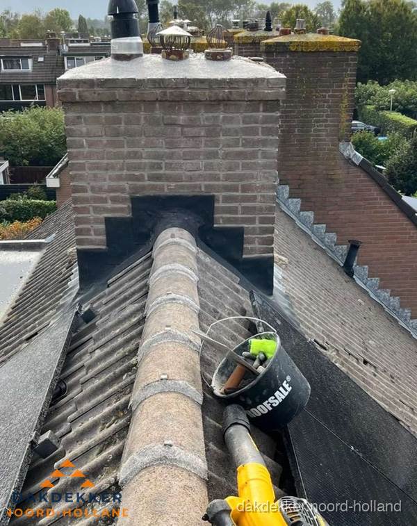 Schoorsteen met loodaansluiting en nokvorst op pannendak in Noord-Holland