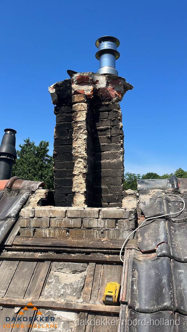 Beschadigde schoorsteen met nieuwe rookgasafvoer op oud dak in Noord-Holland