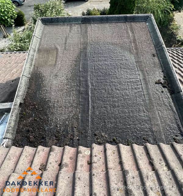 Verouderd plat dak met bitumen en slijtage voor lekkage inspectie in Noord-Holland