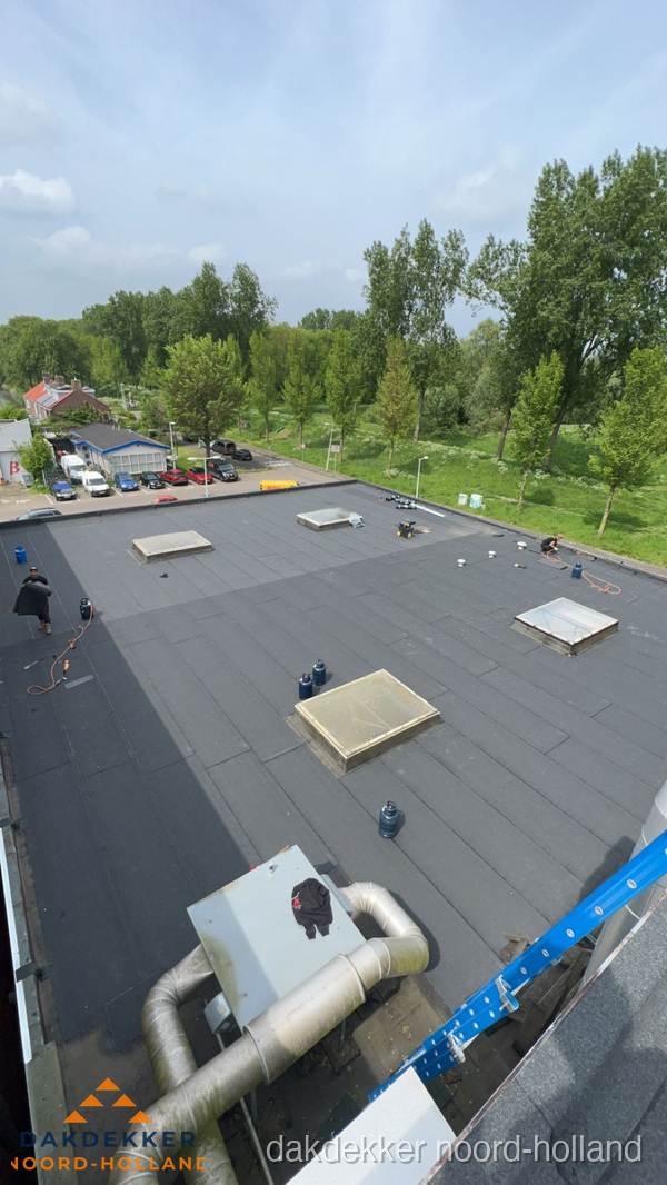 Dakdekker aan het werk op groot plat dak met bitumen in Noord-Holland Dakdekker aan het werk op groot plat dak met bitumen in Noord-Holland