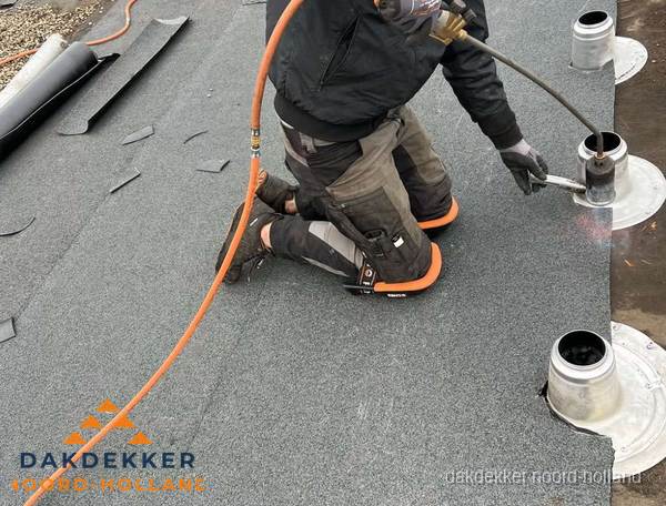 Dakdekker repareert bitumen dakleer bij dakdoorvoer in Noord-Holland