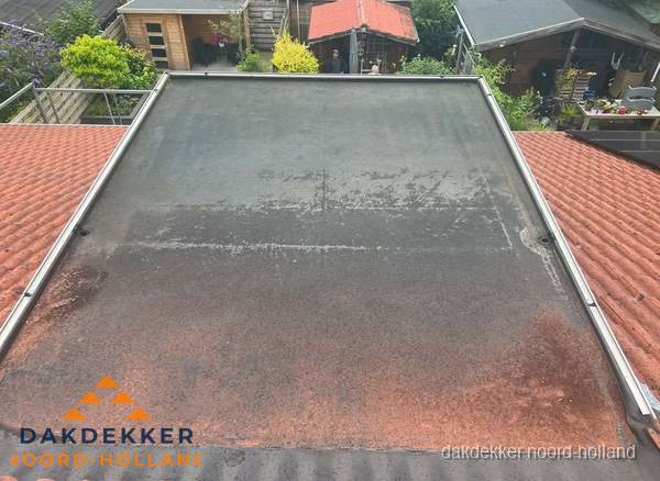 Verouderd plat dak met slijtage tussen schuine daken in Noord-Holland