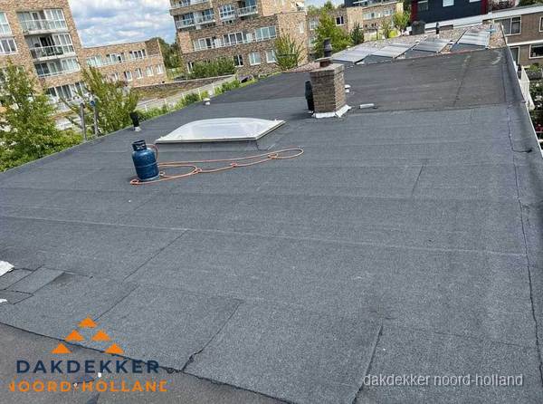 Bitumen dakbedekking op plat dak met lichtkoepel en schoorsteen in Noord-Holland