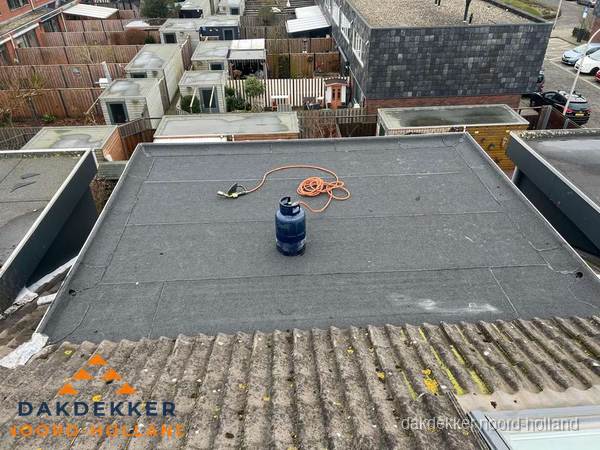 Plat dak met nieuwe bitumen dakbedekking en brandgereedschap in Noord-Holland