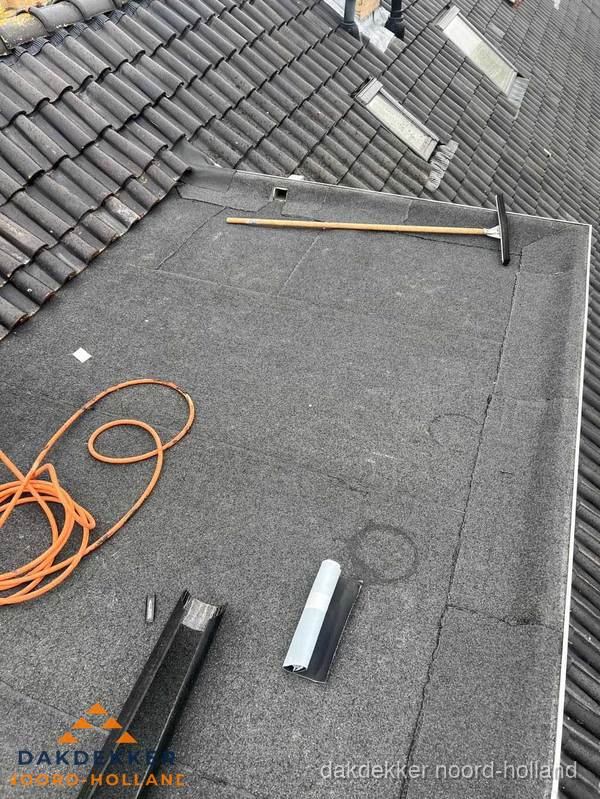 Plat dak reparatie met gereedschap en loodstroken in Noord-Holland