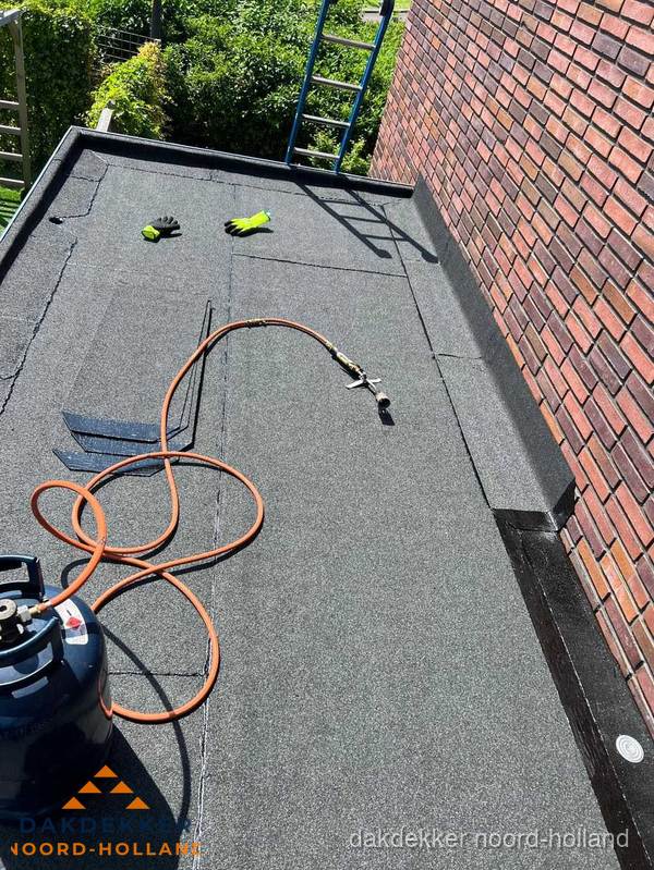 Plat dak met bitumen en brandgereedschap van dakdekkersbedrijf in Noord-Holland